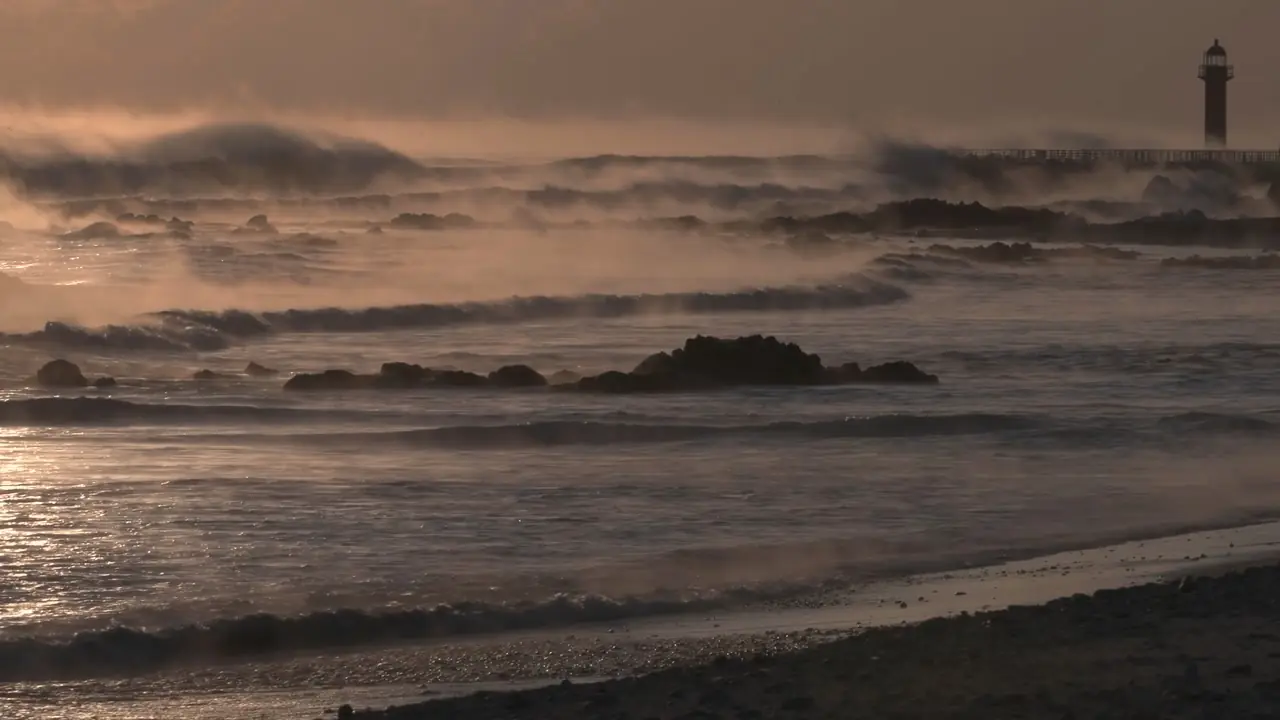 Example frame: waves breaking on a shore, a small lighthouse in the distance